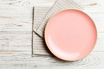 Top view on colored background empty round pink plate on tablecloth for food. Empty dish on napkin with space for your design