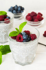 Healthy breakfast or morning with chia seeds vanilla pudding raspberry and blueberry berries on table background, vegetarian food, diet and health concept. Chia pudding with raspberry and blueberry