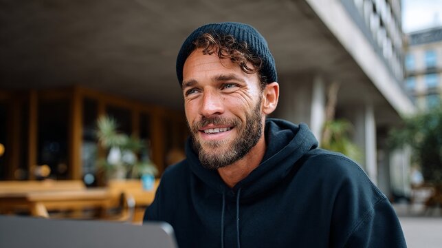 Man sitting at table with laptop, smiling. - Powered by Adobe