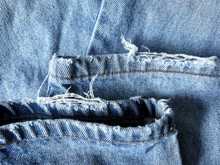 Close-up view of frayed denim fabric with worn seams and distressed texture