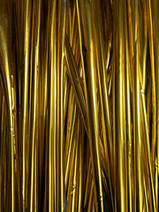 Vertical golden foil strips form a glossy, reflective textured background