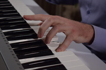A young white man plays an electronic synthesizer indoors, immersed in his creative hobby. Focused on shaping tones and melodies, he explores musical expression and artistry in a calm home setting.
