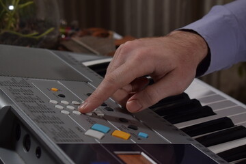 A young white man plays an electronic synthesizer indoors, immersed in his creative hobby. Focused on shaping tones and melodies, he explores musical expression and artistry in a calm home setting.
