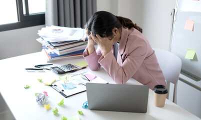 Working Asian women feel stressed, tired from work, migraine headaches from hard work while working...