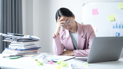 Working Asian women feel stressed, tired from work, migraine headaches from hard work while working at the office
