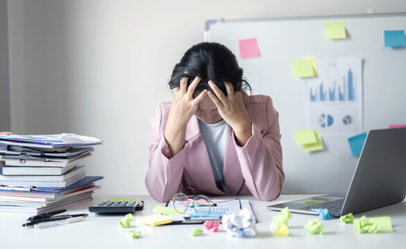 Working Asian women feel stressed, tired from work, migraine headaches from hard work while working at the office