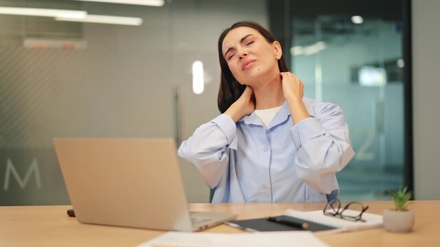Adult at workspace enduring neck pain, discomfort during work on laptop. Emphasizes consequences of prolonged sedentary activity. Illustrates workplace stress, physical strain and fatigue.