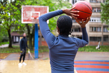 A woman throwing a ball at the basketball court.