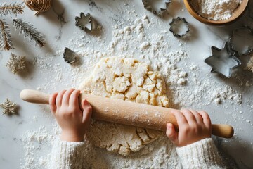 child rolling cookie dough on floured marble countertop with wooden rolling pin, metal cutters and evergreen sprig &mdash; Christmas cookie baking