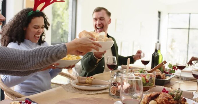 Upon guest reaching for dinner rolls diverse friends passing salad at lantern for festive meal