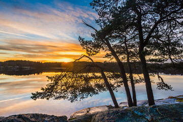 Sunrise over a lake with trees reflecting light near Gothenburg in Sweden