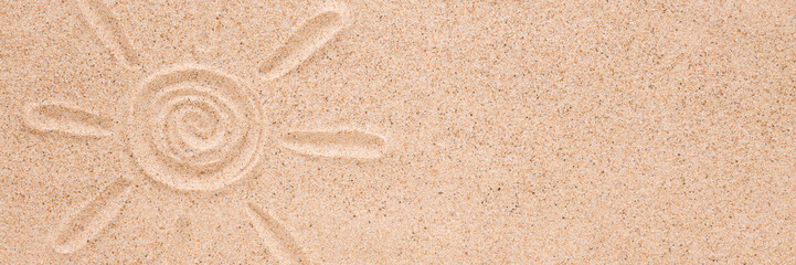 Drawn sun shape with rays on dry light brown sea sand background. Closeup. Wide banner. Summer concept. Empty place for text. Top down view.