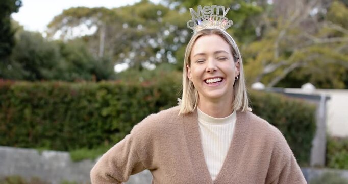 Noticing visitor mid-adult female greeting and laughing tilting head at yard wearing lit Xmas tiara