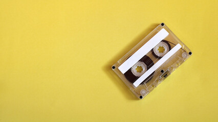Fototapeta premium Cassette tape on yellow background broadcasting retro music