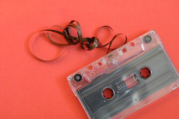 Cassette tape with tangled audio tape on vibrant red surface