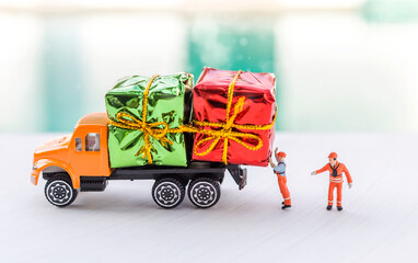 Christmas and New year gift on orange truck with miniature worker over blurred background, gift delivery and shipment, online gift shopping