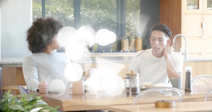 Two men eating food in kitchen bokeh overlay appearing and sparking startled then laughing talk