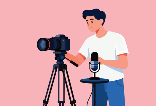 A man in a white shirt sets up a camera on a tripod next to a microphone, pink backdrop