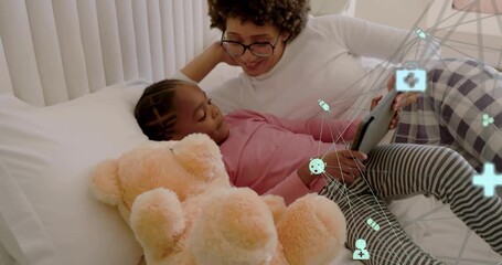 Child tapping tablet and adult woman guiding hands in bedroom, accessing health info icons