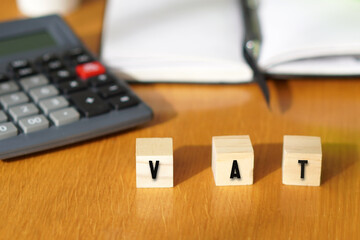 VAT, financial concepts. Letters written on wooden blocks with a calculator and notebook
