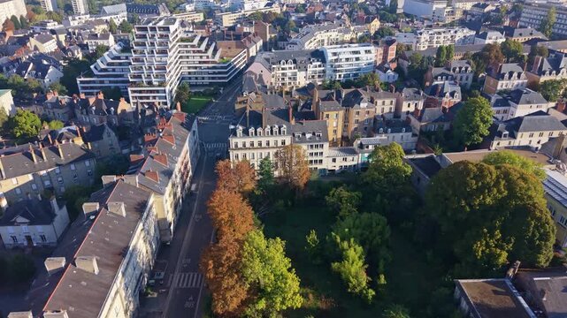 High-angle panoramic drone glide showcasing the dense, historical rooftops and residential blocks of the central Quartier Thabor cityscape in Rennes on a clear, sunny day.