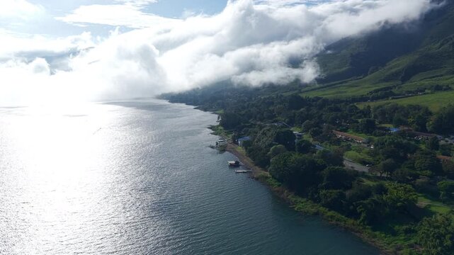 A stunning aerial view over Lago Calima, capturing the serene lake bordered by lush green mountains under a vibrant sky. Ideal for showcasing Colombia's natural beauty in drone video format.