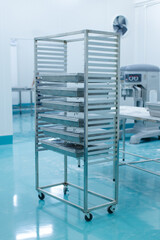 Shelves stainless steel baking rack stacked with metal trays stands bright hygienic production room, Clean modern factory food industry,  technology equipment baking preparation professional workflow.