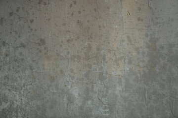 Grungy, cracked concrete wall texture with damp stains and hints of yellow rust and paint remnants.