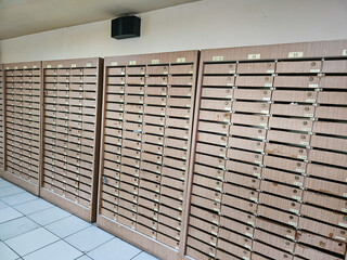 Numerous wooden mailboxes lining a corridor wall in a residential or commercial building, used for mail delivery.