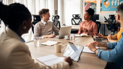 Fototapeta premium Team Collaborating Around a Conference Table in a Modern Office Space