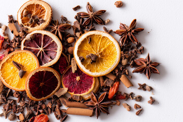 Mixed dried winter spices and citrus fruit slices flat lay isolated on white background. Top view of cinnamon, star anise and ingredients for mulled wine
