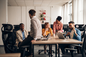 Team Collaborating in Modern Office Environment with Laptops and Discussions