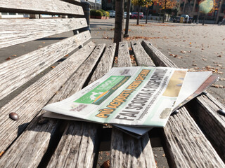 Newspaper on park bench. Special offer in shop. Sales and holidays, Italy. 