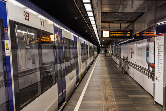 Platform of Leuvehaven metro station in Rotterdam with a RET subway train arriving, showing digital information screens, signs and modern interior. Rotterdam Netherlands, 15 November 2025.