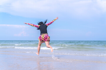 Asian female traveler jumping joyfully on tropical beach