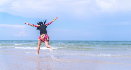 Asian female traveler jumping joyfully on tropical beach