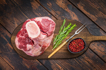 Raw veal shank with bone on wooden board with rosemary and pink pepper rustic background uncooked calf meat for ossobuco