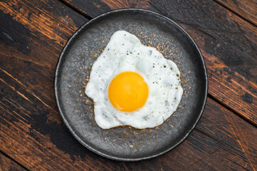 Rustic breakfast scene with hot fried egg on ceramic plate, rich wood texture and balanced overhead composition for food layouts.