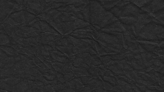Textured black paper surface with crinkled folds creating a dark grungy and abstract background