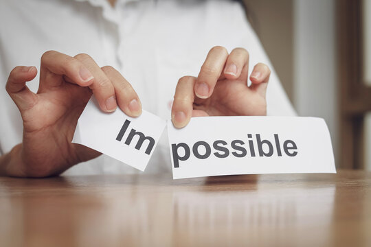 A close-up view of hand tearing the word Im from possible to change its meaning. Business mindset concept, inspiration and determination to make your goals successful.