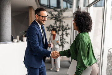 Two Professionals Shaking Hands in a Modern Office Setting