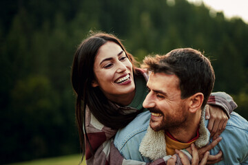 Obraz premium Happy couple enjoying piggyback ride in nature
