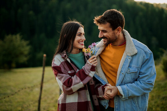 Romantic couple enjoying outdoor date presenting flowers