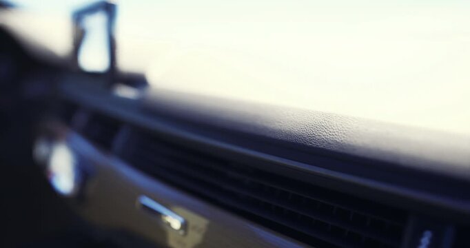 A detailed look at the dashboard of a contemporary vehicle. The sleek design features smooth surfaces and controls, with a bright, open sky visible beyond the windshield.