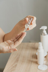 A drop of skin care serum drips onto the palm of the hand, applied with a glass pipette. Beauty, body and face skin care