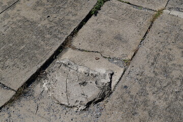 Cracked and Damaged Concrete Patch on Sidewalk with Uneven Paving Stones
