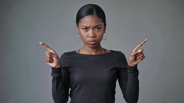 A young woman with a determined look on her face. She is wearing a black top and has her arms crossed. The background is neutral.