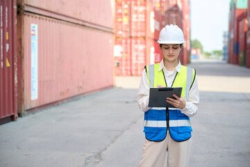 Worker writing on clipboard and checking cargo containers, with a safety vest and helmet