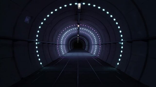 Moving camera into lit circular tunnel, LED arrays shifting color and brightness, showing depth