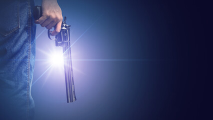 Hand holding a gun with a spotlight on a dark background. Concept of gun violence, tension, crime,...